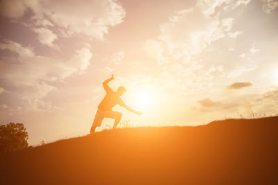 Silhouette man standing on beach against sky during sunset