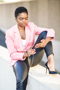 Businesswoman using mobile phone while sitting on retaining wall
