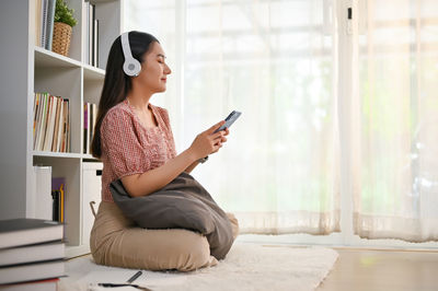 Young woman using mobile phone while sitting on sofa at home