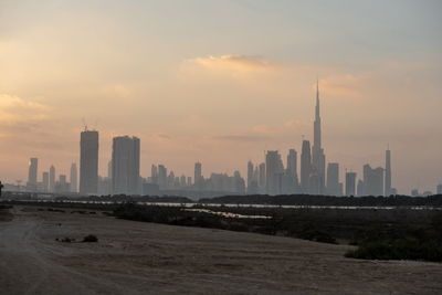 Modern buildings in city against sky during sunset