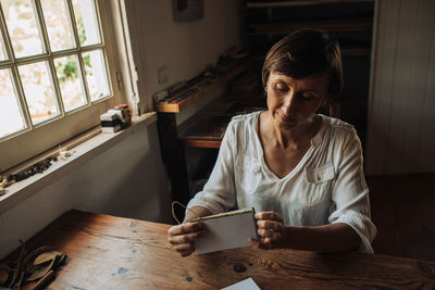 Female artisan sitting at table and stitching sheets of paper