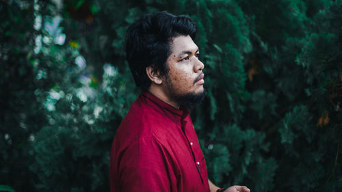 Side view of young man looking away in forest