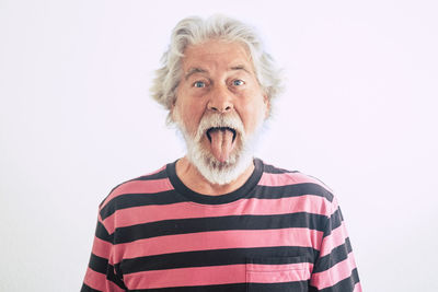 Portrait of man sticking out tongue against white background