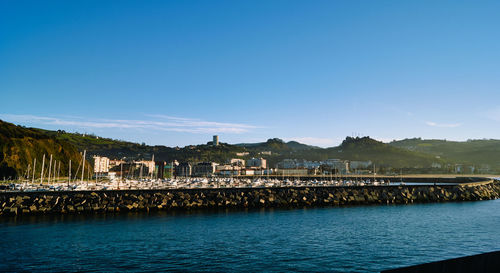 Scenic view of river by buildings against blue sky