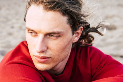 Close-up of thoughtful young man looking away at beach