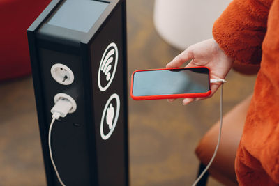 Midsection of woman charging mobile phone