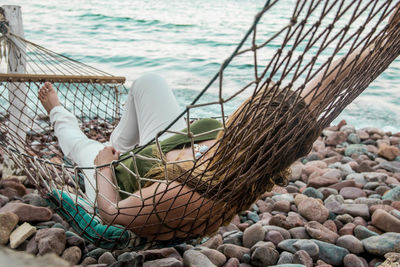 Woman relaxing on hammock by sea at beach