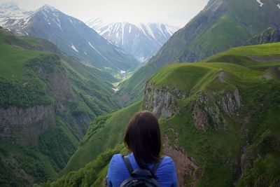 Rear view of woman standing on mountain against sky