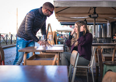 Couple with wineglasses on table talking at outdoor cafe