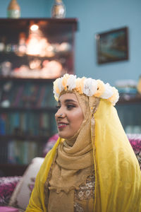 Bride wearing traditional clothing looking away at home