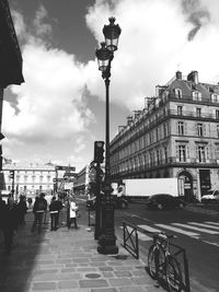 Street light in city against cloudy sky