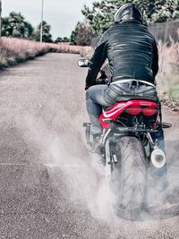 Rear view of man riding motorcycle on road
