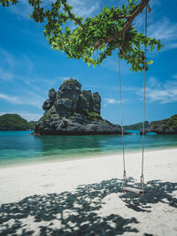 Relaxing swing on white sand beach of stunning rock formation island. mu koh ang thong, thailand.