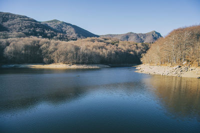 Scenic view of lake by mountains against clear sky