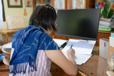 Rear view of woman using laptop at table