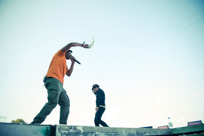 Low angle view of men standing against clear sky