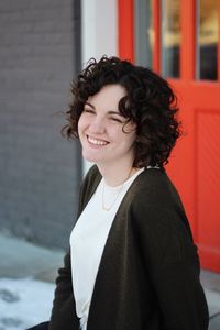 Portrait of smiling young woman standing against built structure