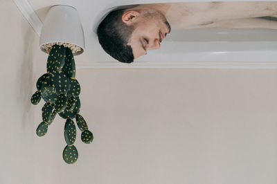 Upside down image of shirtless man in bathtub