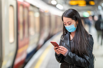 Young woman using phone while standing on train