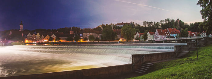 Fountain in park by lake against sky in city