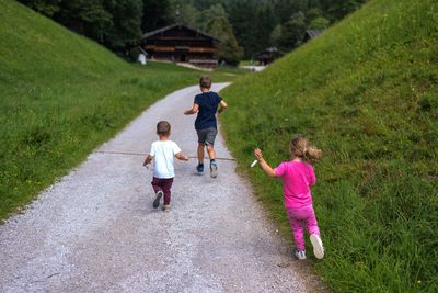 Rear view of siblings running on footpath at park