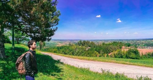 Scenic view of road by trees on field against sky