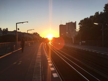 Railroad tracks in city against sky during sunset