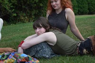 Mother and daughter sitting on grassy field