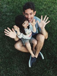 High angle view of father and daughter sitting on grassy field