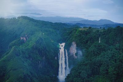 Scenic view of waterfall against cloudy sky