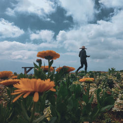 Man standing on field against cloudy sky