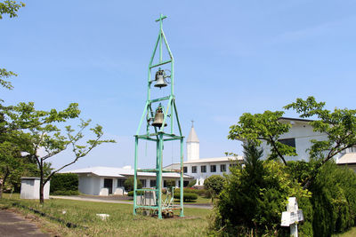 Trees and buildings against clear blue sky