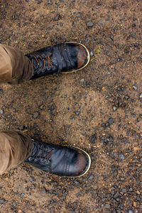 Low section of man standing on dirt road outdoors