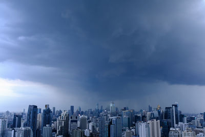 Aerial view of modern buildings in city against cloudy sky