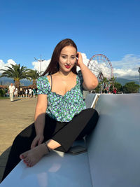 Portrait of young woman sitting on sofa at park