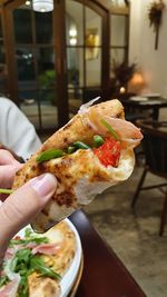 Delicious italian handmade pizza, prosciutto and arugula leaves, eating,closeup,hand holding food