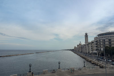 View of buildings at waterfront against cloudy sky