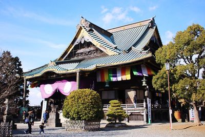 Traditional building by trees against sky