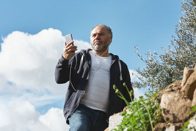 Handsome mature man having video call or listening to music with cellphone. modern technologies.