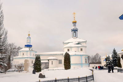 Tower amidst buildings against sky during winter