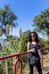 Low angle view of young woman standing against trees