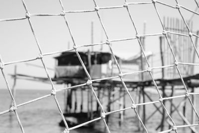 Detail shot of fence against blurred stilt structure in water