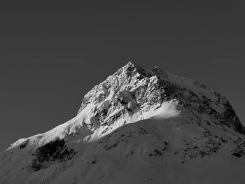 Low angle view of snowcapped mountain against clear sky