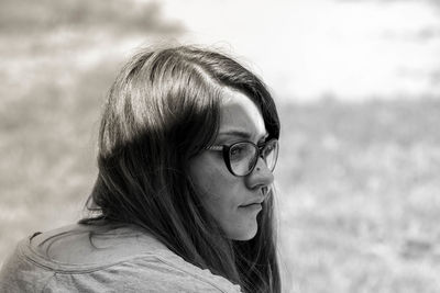 Rear view of thoughtful young woman wearing eyeglasses looking away outdoors