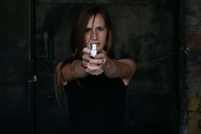 Portrait of young woman shooting with gun