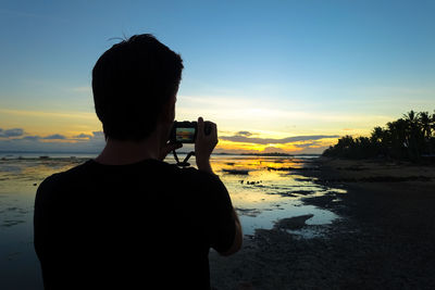 Rear view of man photographing at beach