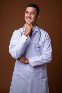 Doctor standing against brown background