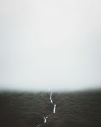 Scenic view of land against sky in foggy weather