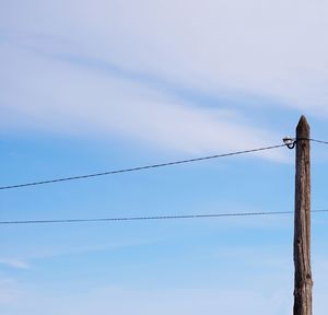Old wooden pole with telephone wires against the sky with clouds