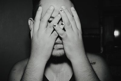 Close-up of man looking through fingers